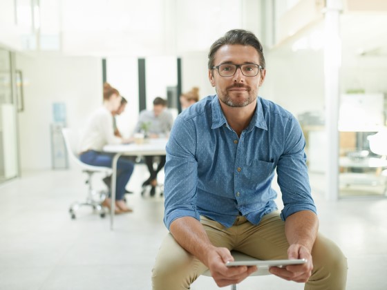 Mann im Büro hält Tablet in der Hand