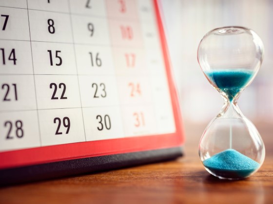 Kalender im Hintergrund mit Sanduhr im Vordergrund
